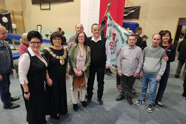 Pani Wójt, Pani Dyrektor i mieszkańcy domu na hali ze sztandarem.