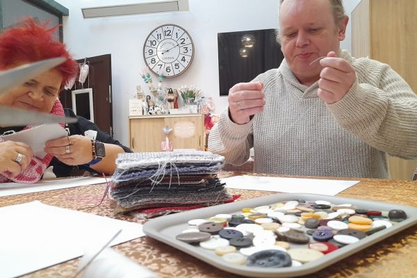 Mieszkaniec przyszywa guziki.