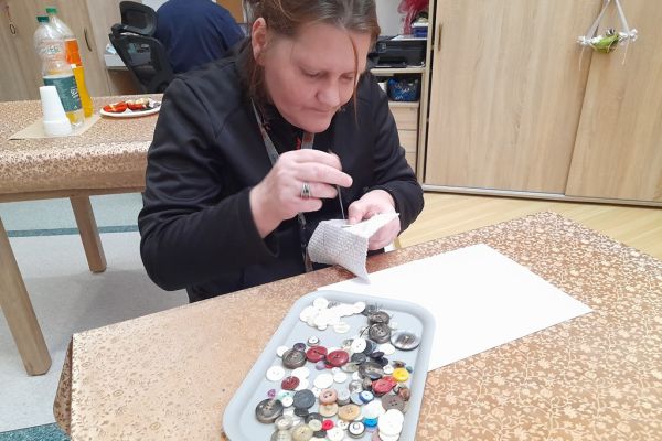 Mieszkaniec przyszywa guziki.