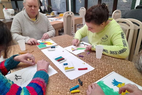 Mieszkańcy wyklejają obrazek plasteliną.