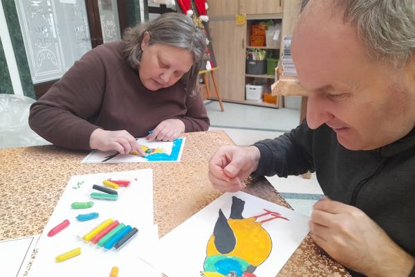 Mieszkańcy wyklejają obrazek plasteliną.