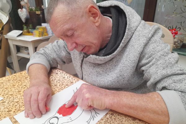 Mieszkaniec wykleja obrazek plasteliną.