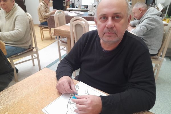 Mieszkaniec wykleja obrazek plasteliną.