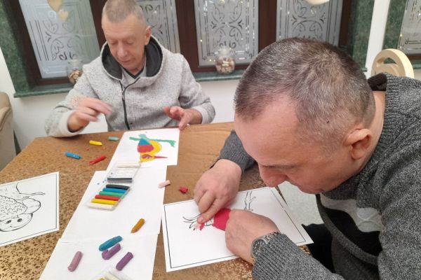 Mieszkańcy wyklejają obrazek plasteliną.