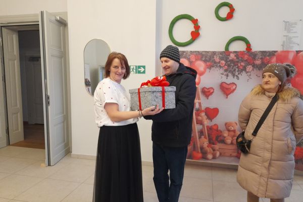 Mieszkaniec wręcza prezęt pani prowadzącej bal.