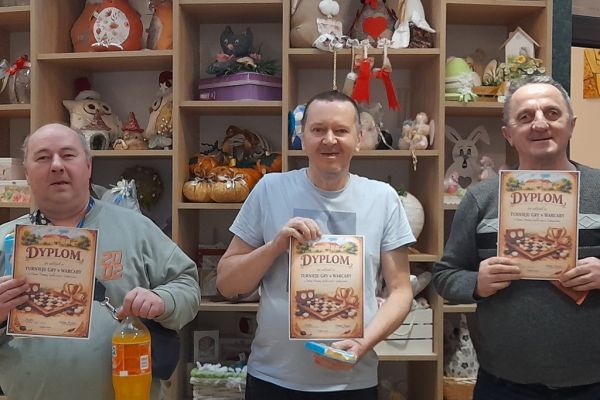 Trzech mieszkańców stoi z dyplomami.