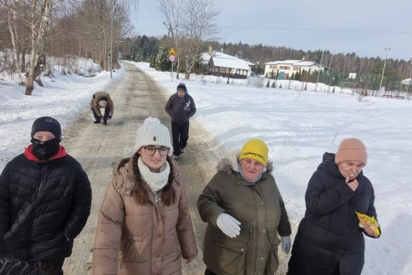 Mieszkańcy spacerują ze znajomymi drogą wśród pól zaśnieżonych.