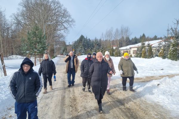 Mieszkańcy spacerują ze znajomymi drogą wśród pól zaśnieżonych.