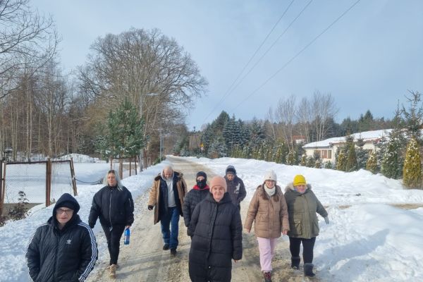 Mieszkańcy spacerują ze znajomymi drogą wśród pól zaśnieżonych.