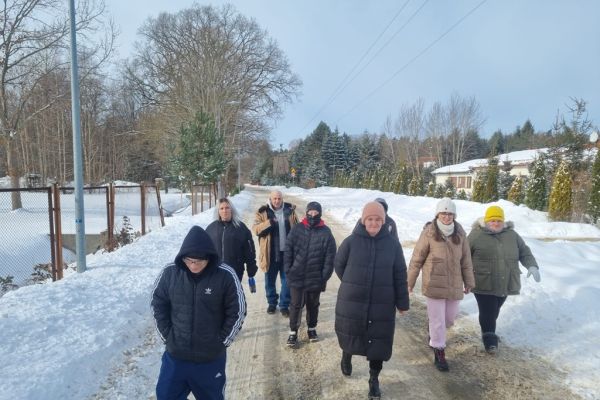 Mieszkańcy spacerują ze znajomymi drogą wśród pól zaśnieżonych.
