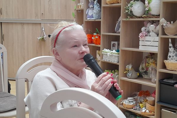 Mieszkanka śpiewa siedząc na krześle.