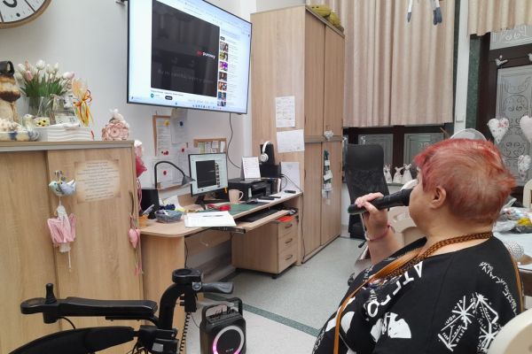 Mieszkanka śpiewa siedząc na krześle.