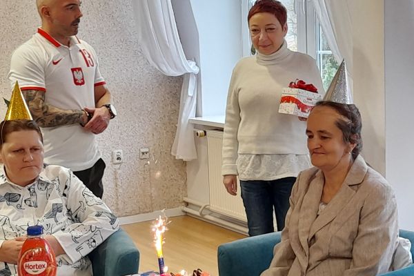 Mieszxkańcy świętują urodziny przy suto zastawionym stole.