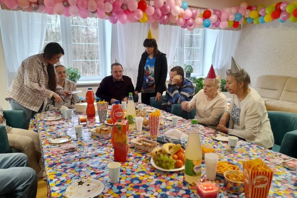 Mieszxkańcy świętują urodziny przy suto zastawionym stole.