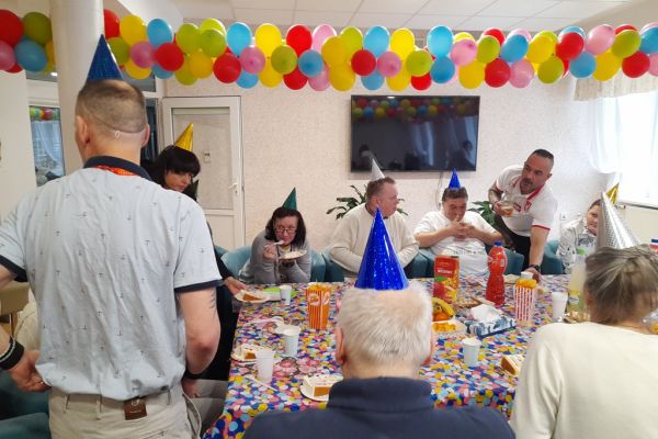 Mieszxkańcy świętują urodziny przy suto zastawionym stole.