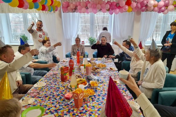 Mieszxkańcy świętują urodziny przy suto zastawionym stole. Toast.