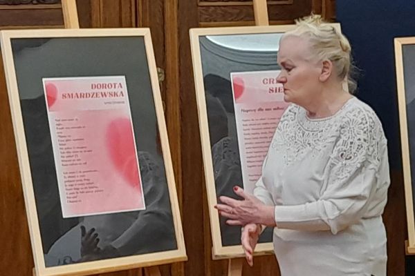 Mieszkanka stoi przy sztaludze ze swoim wierszem.