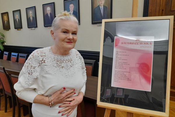 Mieszkanka stoi przy sztaludze ze swoim wierszem.