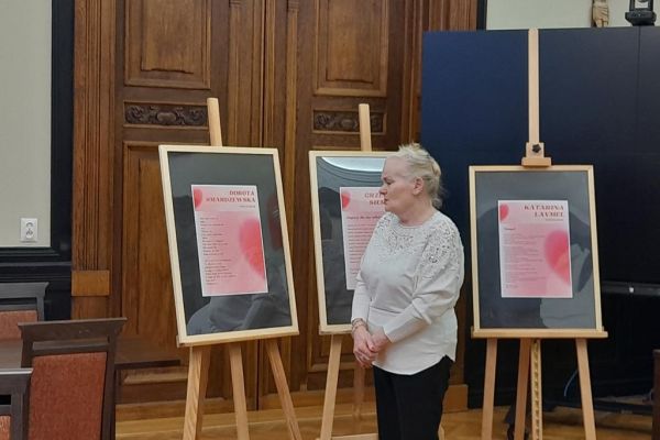 Mieszkanka stoi przy sztaludze ze swoim wierszem.