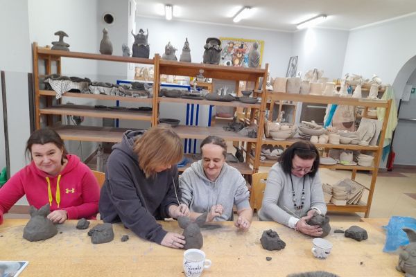 Mieszkańcy w pracowni lepią w glinie.
