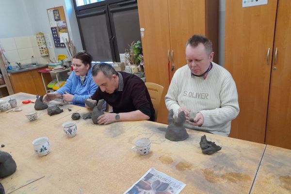 Mieszkańcy w pracowni lepią w glinie.