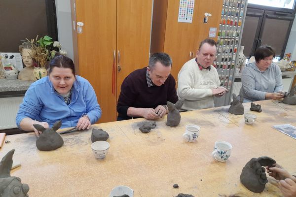 Mieszkańcy w pracowni lepią w glinie.