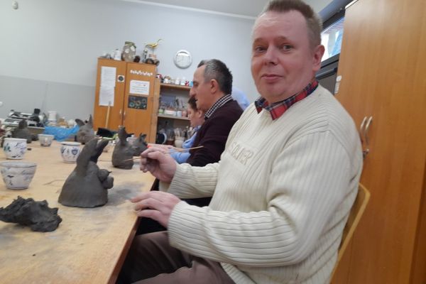Mieszkańcy w pracowni lepią w glinie.