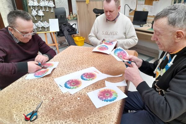 Mieszkańcy wycinają kwiaty z papieru.