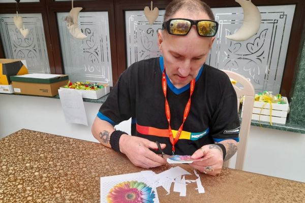 Mieszkaniec wycina kwiaty z papieru.