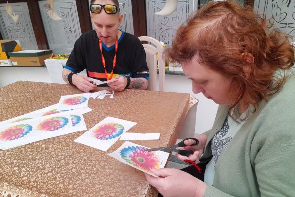 Mieszkańcy wycinają kwiaty z papieru.