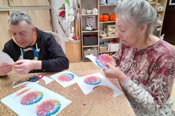 Mieszkańcy wycinają kwiaty z papieru.
