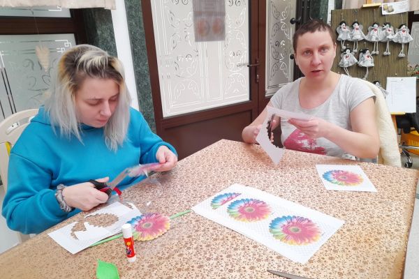 Mieszkańcy wycinają kwiaty z papieru.