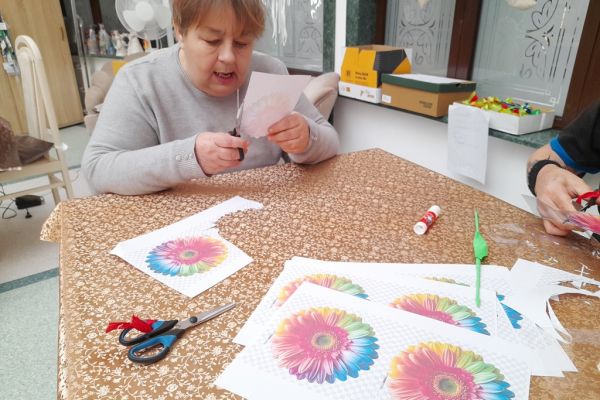 Mieszkańcy wycinają kwiaty z papieru.
