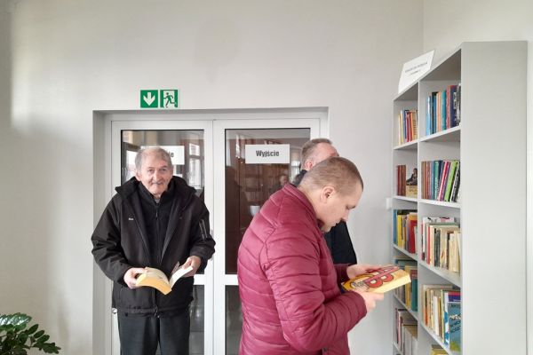 Mieszkańcy stoją z książkami w czytelni.