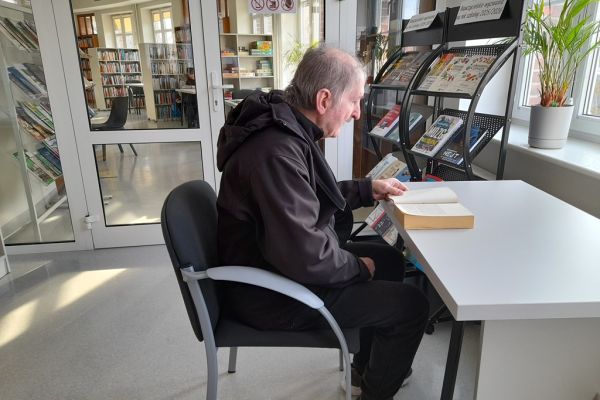 Mieszkaniec siedzi i czyta w czytelni.