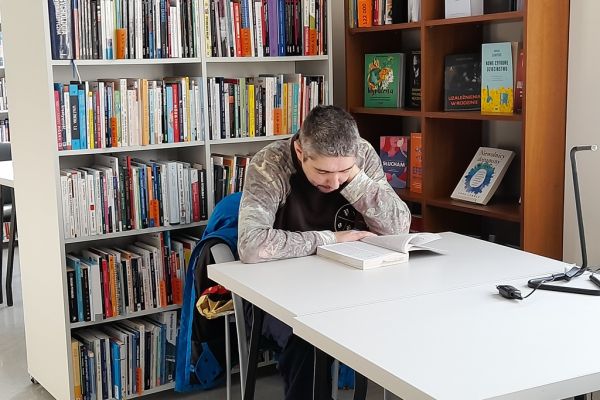 Mieszkaniec siedzi i czyta w czytelni.