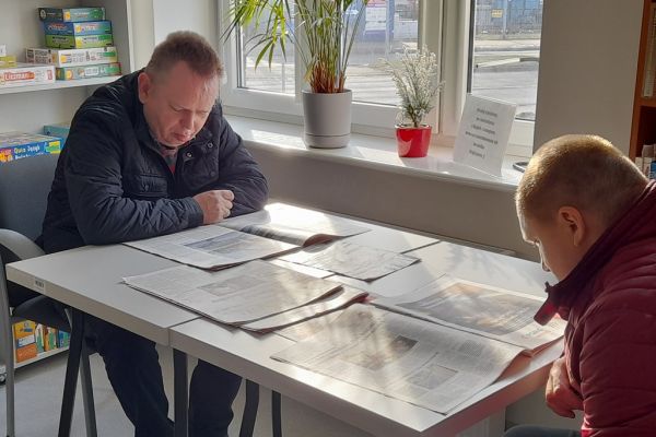 Mieszkańcy siedzą i czytają w czytelni.