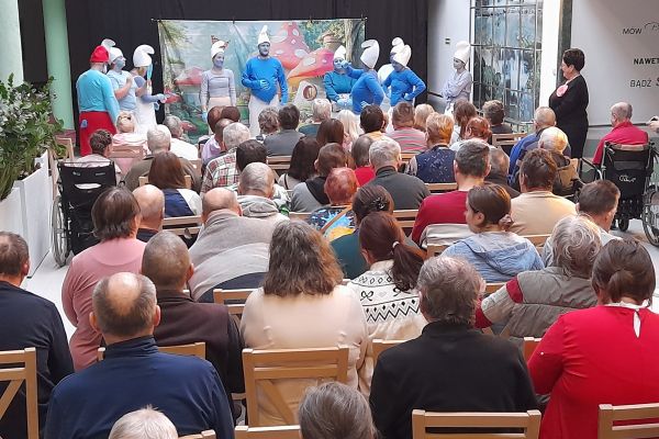  Mieszkańcy oglądają występujacych aktorów w strojach smerfów.