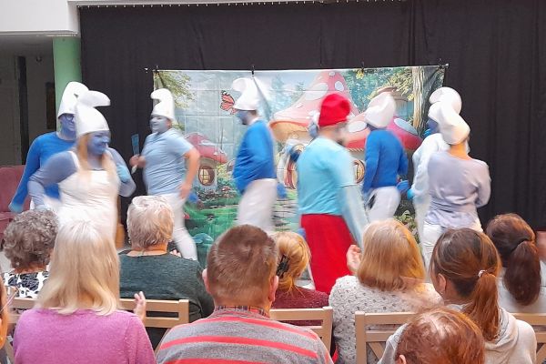  Mieszkańcy oglądają występujacych aktorów w strojach smerfów.