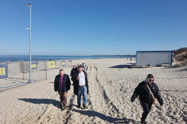 Mieszkańcy ida po plaży.