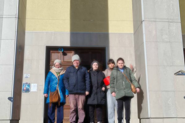 Mieszkańcy stoją przed wejściem do kościoła.