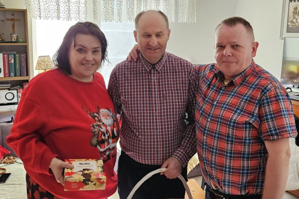 Obdarowana pani z prezentem wraz z dwoma mężczyznami.