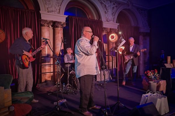 Uczestnicy spotkania na scenie , zespół spiewający.