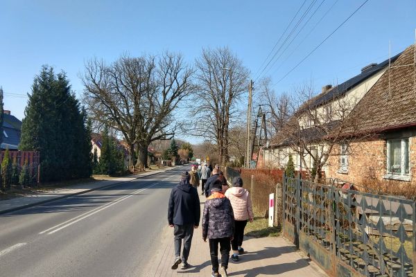 Mieszkańcy spacerują chodnikiem we wiosce.