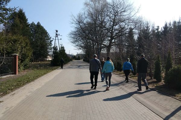 Mieszkańcy spacerują chodnikiem we wiosce.