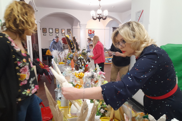 Pani ogląda prace plastyczne mieszkańców.