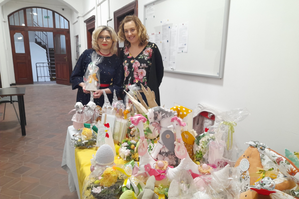 Terapeutka stoi wraz z panią oglądająca a przed nimi na stole prace mieszkańców.