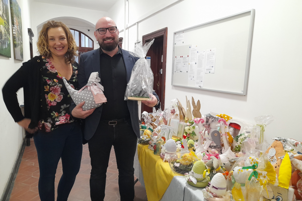 Terapeutka stoi ze Starostą który trzyma prace mieszkańców a obok na stole inne prace.