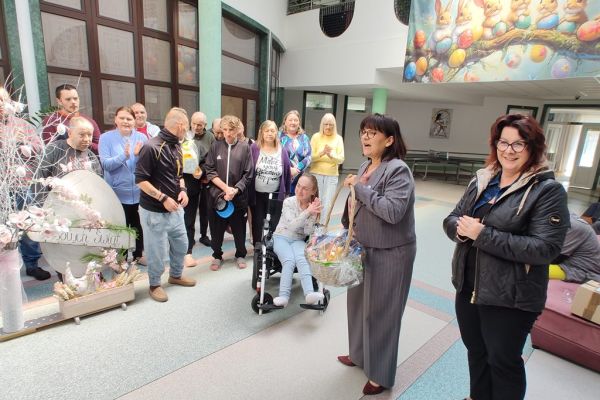 Mieszkańcy stoją na holu domu podczas kiedy Pani Wójt składa im życzenia.