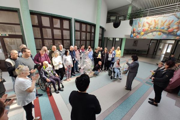 Mieszkańcy stoją na holu domu podczas kiedy Pani Wójt składa im życzenia.